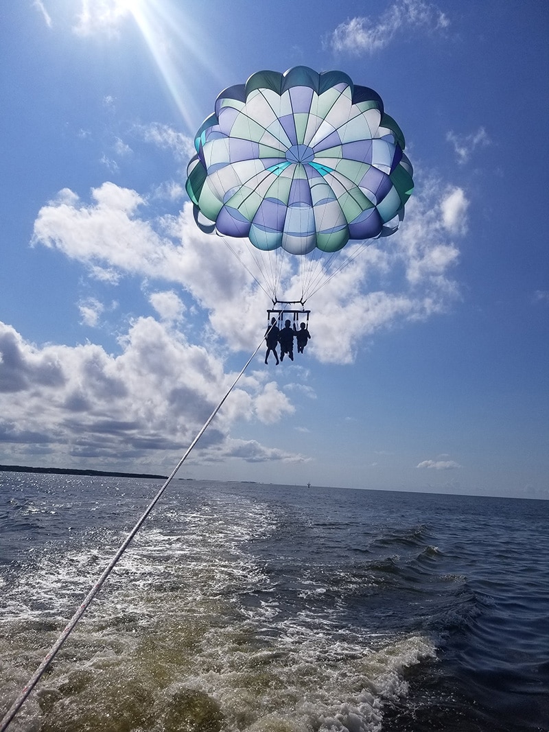 Three People Parasailing Over Ocean